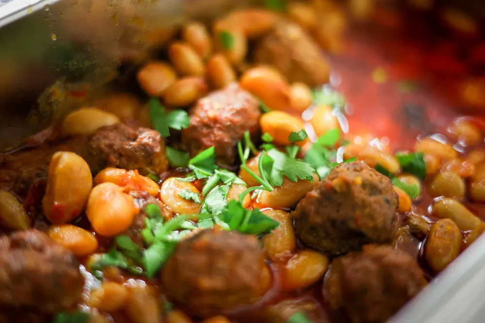 Haricots coco blancs mijotés à la tomate avec boulettes de viande et persil dans un plat