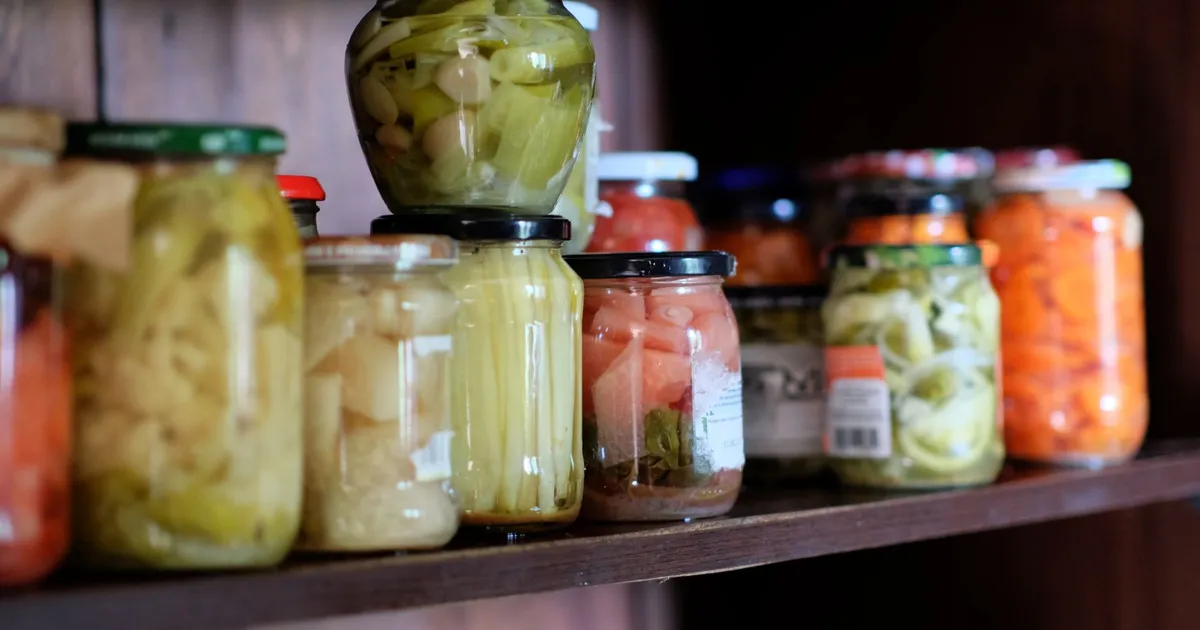 Étagère de bocaux de conserves maison datés dans un cellier