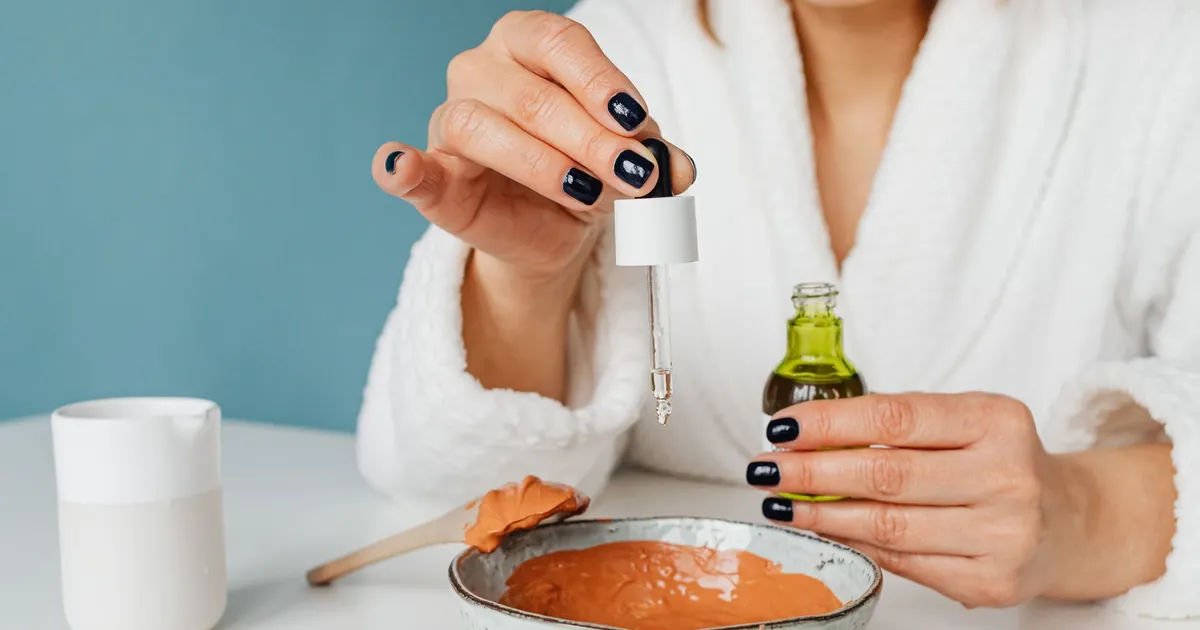 Mains préparant un masque à l'argile maison avec des huiles naturelles