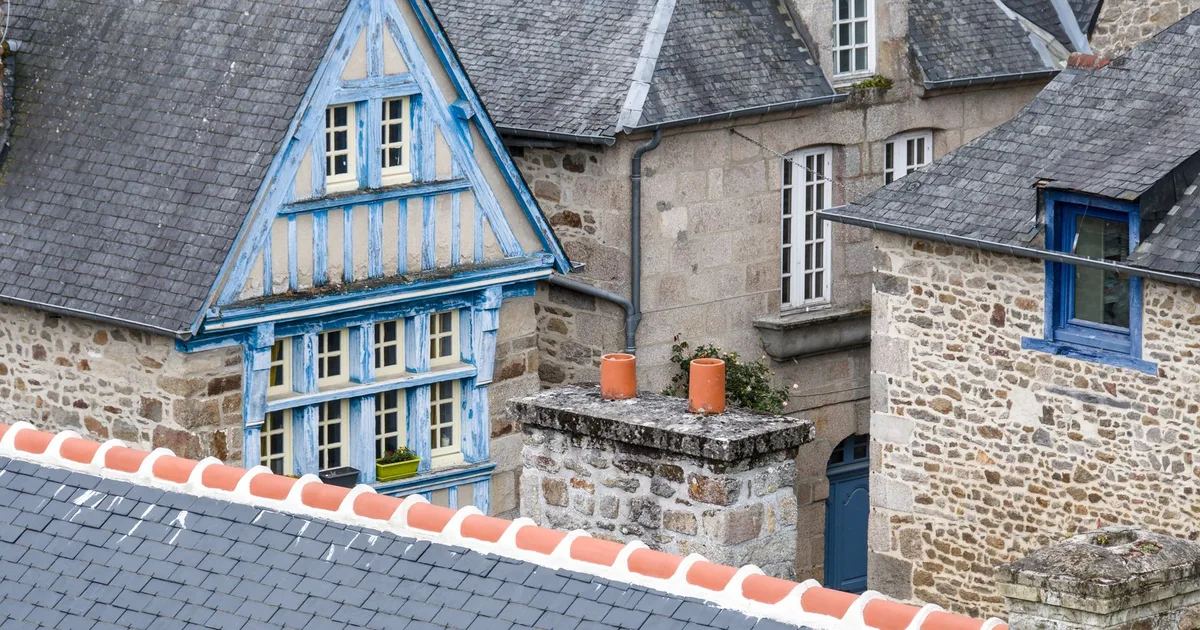 Façade d'une petite école de village en pierres en Bretagne, jardin en avant-plan