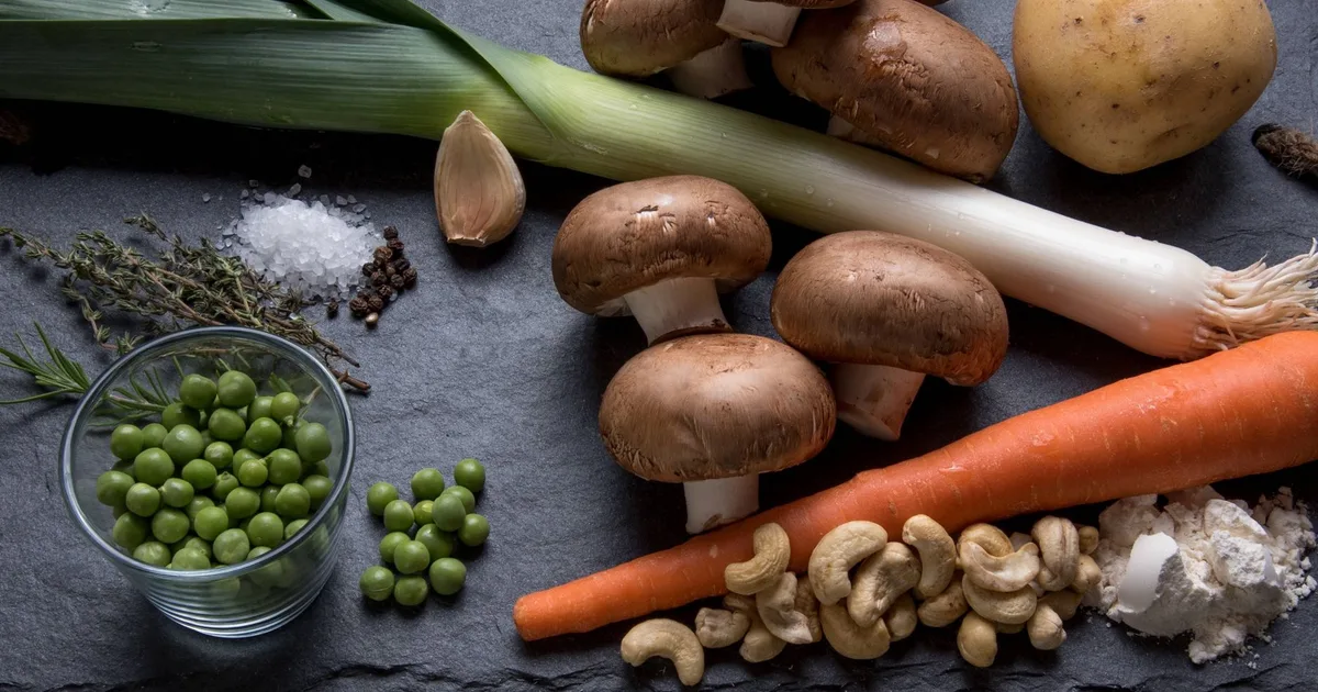 Poireaux, champignons bruns, petits pois et carottes sur ardoise sombre, garnitures pour galette de sarrasin