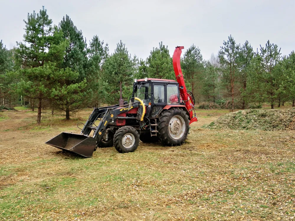 Broyeur tracté avalant des branches sur un grand terrain