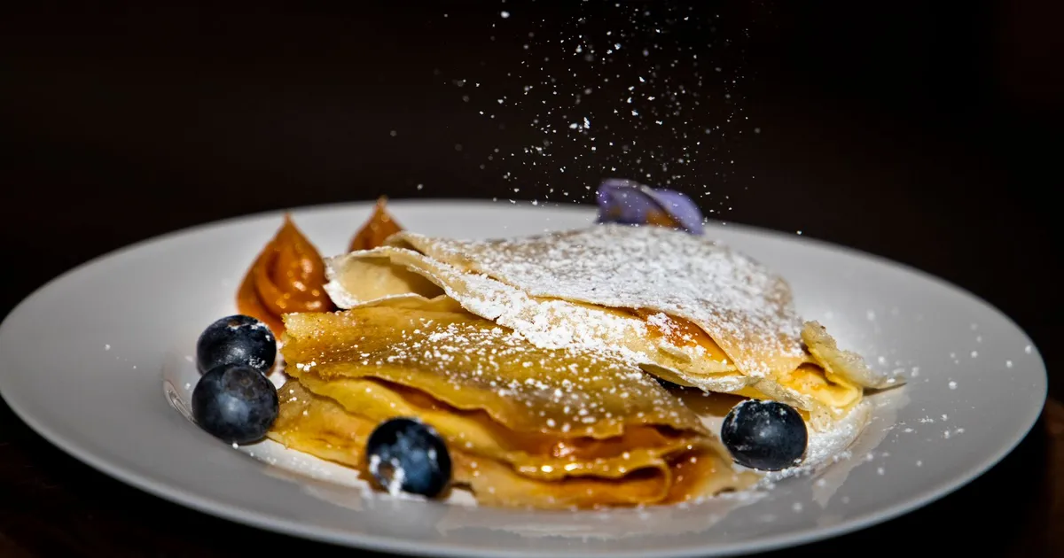 Crêpes fines maison servies avec des myrtilles et du sucre glace