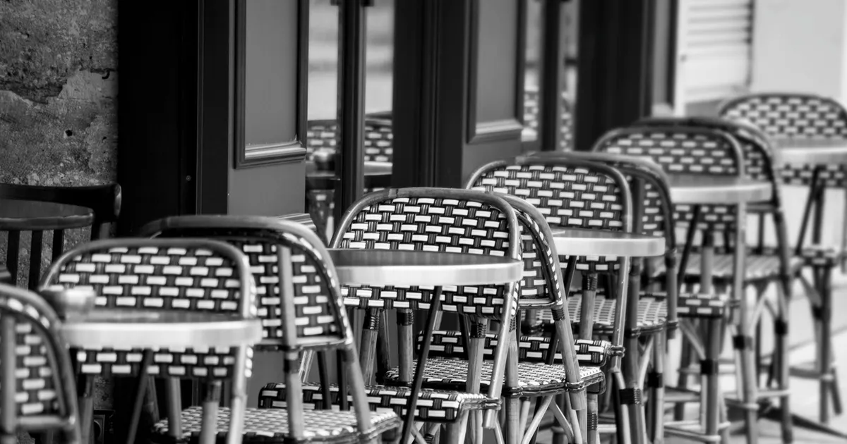 Terrasse de café avec chaises en osier tressé, ambiance méridionale